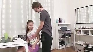 Young brunette guy wearing gray shirt gets to know swet brunette and massages her back while she sits on the chair wearing pink top and purple skirt